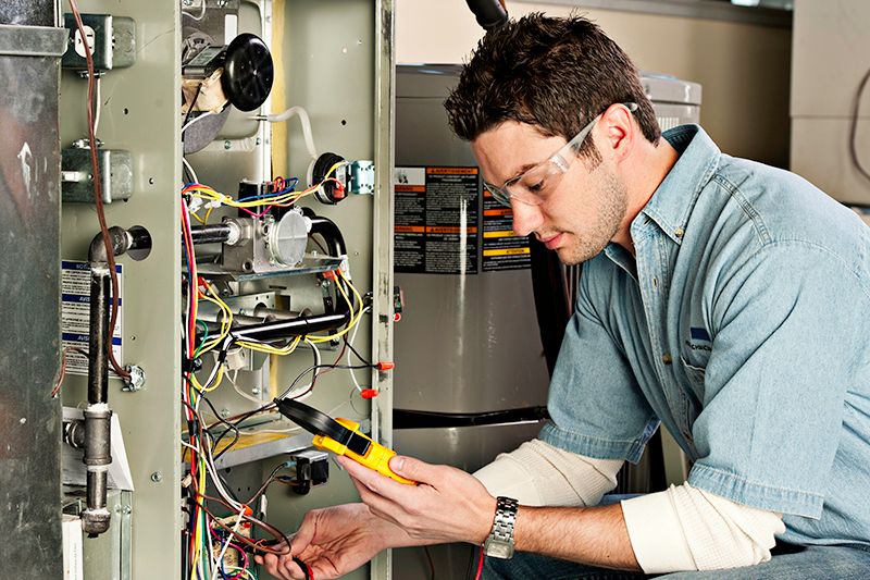 Image of someone working on a furnace. Why Do I Need AC Maintenance Now?
