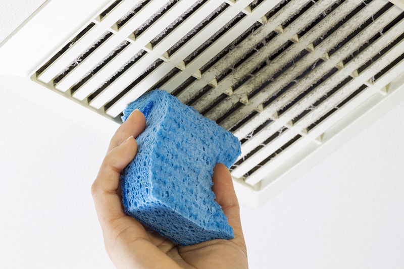 blue sponge being wiped across dirty vent